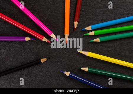 Group of twelve whole colored pencil flatlay on grey stone Stock Photo