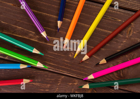 Group of twelve whole colored pencil flatlay on brown wood Stock Photo