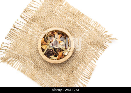 Lot of pieces of lingonberry strawberry fruit tea in wooden bowl on jute cloth flatlay isolated on white background Stock Photo