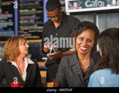 Cheerful adult female with friend in coffee house Stock Photo