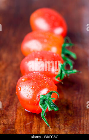 macro images of four wet tomatoes closeup on wooden table Stock Photo