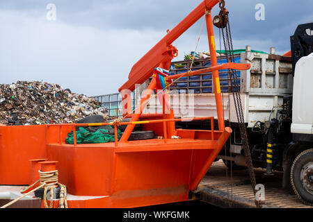 Boat collecting trash from the ocean beach in Thailand Stock Photo