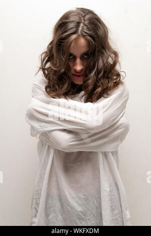 Young insane woman with straitjacket standing looking at camera Stock Photo
