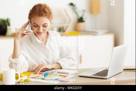 Dressmaker speaking on cellphone and looking at palette Stock Photo