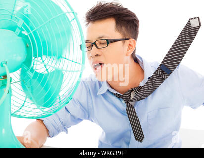 Young man cooling face under wind of fan Stock Photo