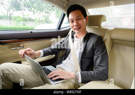 Successful young man using laptop while sitting in car Stock Photo