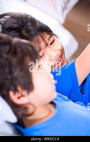 Big sister taking care of her disabled little brother on mat Stock Photo