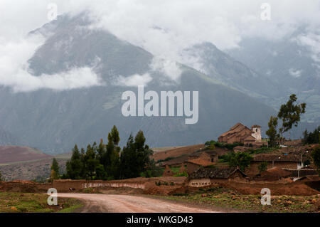 Small village in the Andes. Small structures against the mountains which tops are covered by clouds. Stock Photo