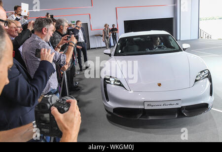 04 September 2019, Brandenburg, Neuhardenberg: The Porsche Taycan will be presented to the public for the first time at the world premiere of the automobile group in a hall on the airport in Neuhardenberg. On Wednesday, the first purely electric model from Stuttgart-Zuffenhausen will celebrate its world premiere simultaneously on three continents. It will be delivered at the end of the year, the USA will make the start. The expectations are high. Porsche, like the industry as a whole, has been criticised for the diesel scandal and the debate about driving bans and is viewed with skepticism. Ph Stock Photo