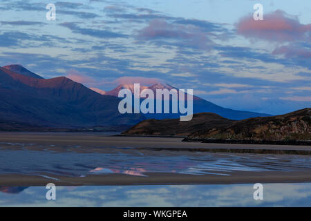 The view from Durness over the Kyle of Durness at sunrise. Beinn Spionnaidh, the snow-capped mountain in the background, lit by the rising sun. In the Stock Photo