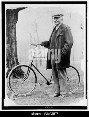 John D. Rockefeller, full-length portrait, standing with a bicycle Stock Photo