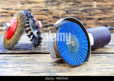 Angle grinder with grinding disc brushes and abrasive wire brushes lies on the background of a wooden table in a blur.. Stock Photo