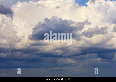 Thunderclouds float in the sky, gathering together and hide the blue sky. Stock Photo