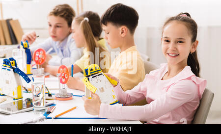 Happy schoolgirl holding robot model in classroom Stock Photo