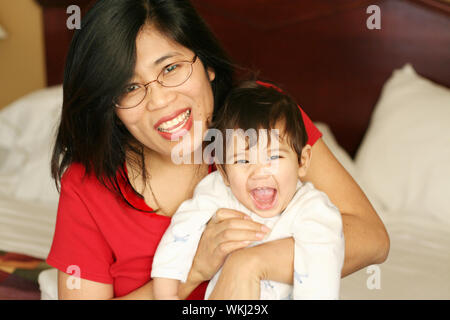 Asian mother and baby waking up with smiles Stock Photo