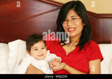 Asian mother and baby waking up with smiles Stock Photo