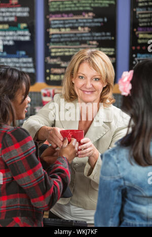 Smiling restaurant cashier serving drinks to customers Stock Photo
