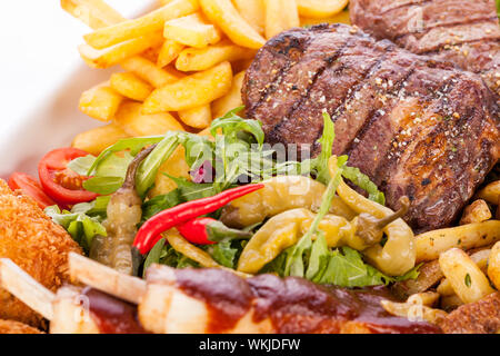 Platter of mixed meats, salad and French fries Stock Photo