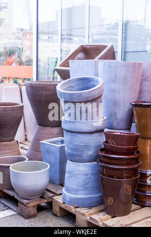 Glazed and unglazed ceramic flower pots in a variety of sizes and colors stacked on wooden pallets outside a pottery, warehouse or commercial store Stock Photo