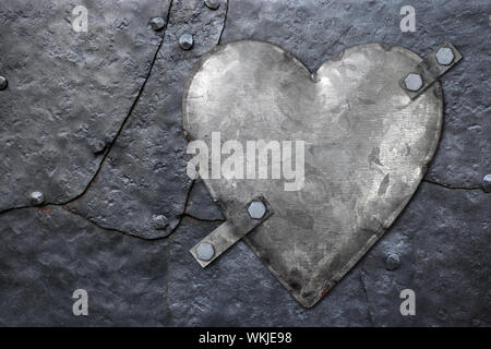 Photo of a galvanized metal heart bolted to old hammered metal plates with rivets. Stock Photo