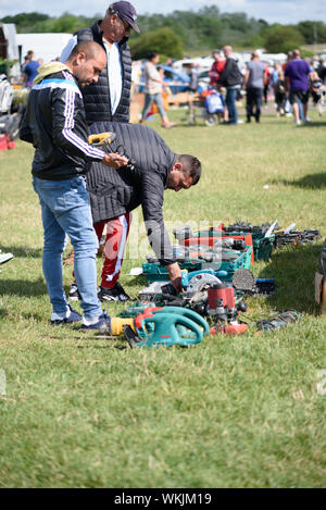 CHELMSFORD, ESSEX/ENGLAND - 1ST JUNE 2019 - Men visiting a car boot sale in Boreham Essex where they are looking at drills and tools for work and can Stock Photo