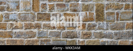 Old stone wall made of square natural stones in rows Stock Photo