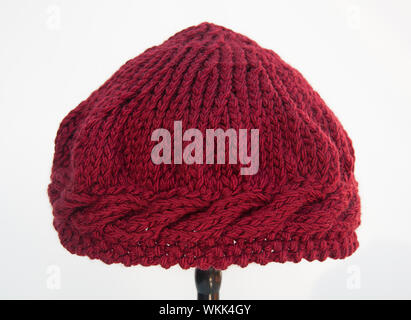 Burgundy wine knit hat isolated on white background.  This fiber art is made of wool yarn in deep maroon color with cable stitches around the brim are Stock Photo