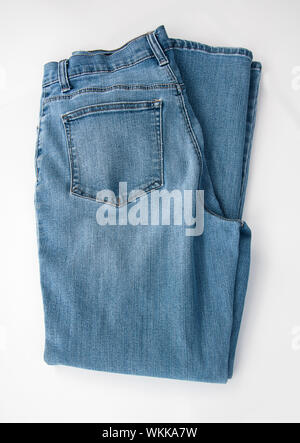 Pair of denim blue jeans folded and isolated on a light background.  A classic staple of casual fashion clothing. Stock Photo