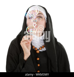 Young nun on white background blowing bubbles Stock Photo