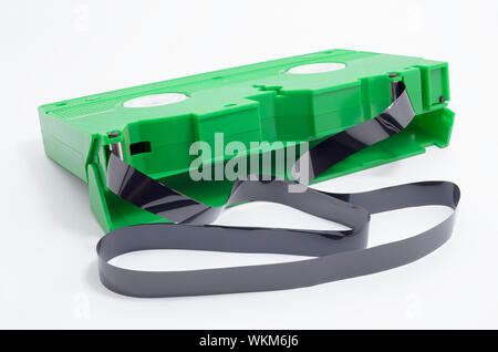 VHS tape with open cover and the magnetic tape rolled out of the spool, out of the tape. Green VHS, Video Home System. Stock Photo