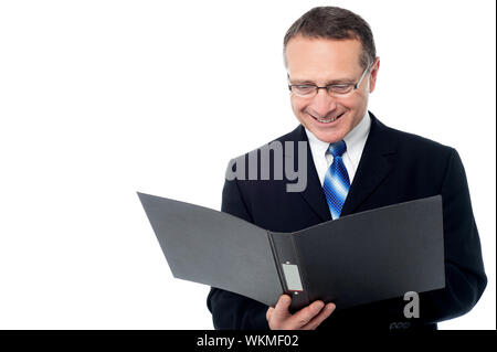 Aged businessman wearing glasses, reading a business report Stock Photo