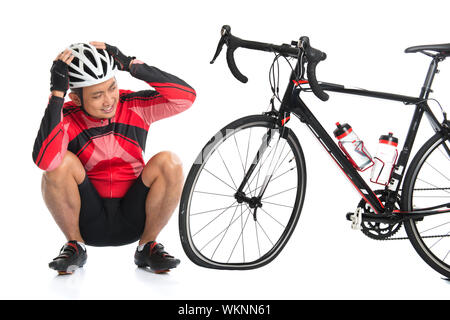 Asian cyclist headache and looking at his flat tire bike, isolated on white background. Stock Photo