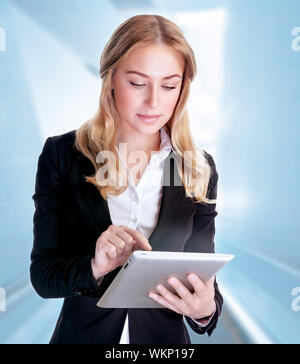 Portrait of beautiful serious business woman using touchpad, modern electronic technology, working in the office, conception of success Stock Photo