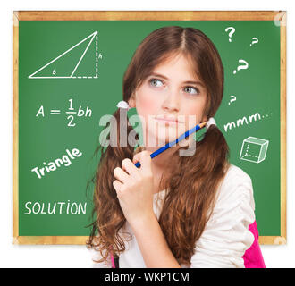 A teenage schoolgirl is thinking while standing blackboard, a 10-12 ...