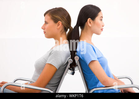 Close-up of two businesswoman sitting in chairs to back