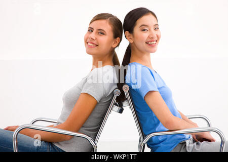 Two happy businesswoman sitting in chairs to back