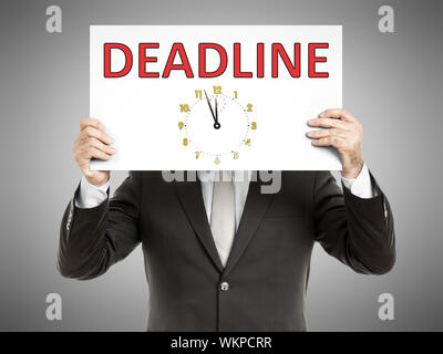 A business man holding a paper in front of his face with the text deadline Stock Photo