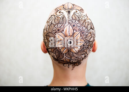 Drawing process of henna mehndi tattoo on womans bald head Stock Photo