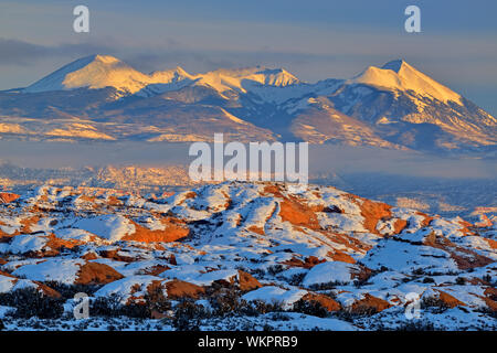 Fresh snow on the petrified dunes with the La Sal Mountains near sunset, Arches National Park, Utah, USA Stock Photo