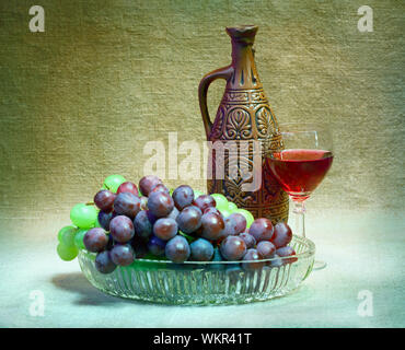 Still-life from grapes, bottle and glass of wine on canvas background Stock Photo
