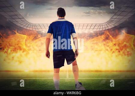 Handsome football player in blue jersey against large football stadium with lights Stock Photo