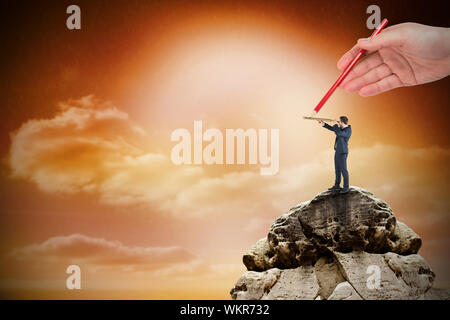 Composite image of hand drawing businessman against large rock overlooking orange sky Stock Photo