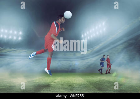 Football player in red jumping against football stadium Stock Photo