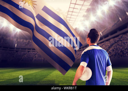 Handsome football player in blue jersey against football stadium Stock Photo