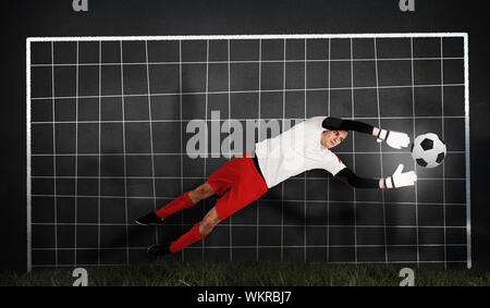 Composite image of fit goal keeper jumping up against goal net Stock Photo