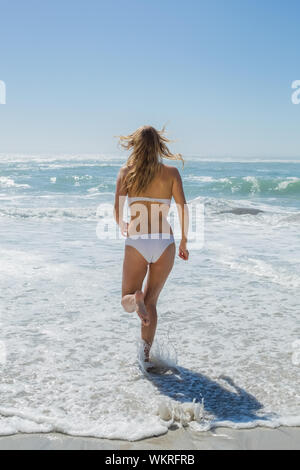 Gorgeous blonde in white bikini running to the sea on a sunny day Stock Photo