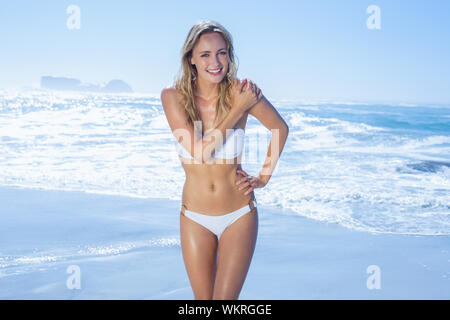 Gorgeous blonde in white bikini standing by the sea on a sunny day Stock Photo