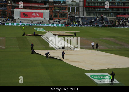 MANCHESTER, ENGLAND. 04 SEPTEMBER 2019: Ground staff struggle with rain covers in the wind at lunch during day one of the 4th Specsavers Ashes Test Match, at Old Trafford Cricket Ground, Manchester, England. Stock Photo