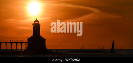 Michigan City, Indiana  USA / 08-25-2019:  Washington Park Iconic Lighthouse Silhouette during a Dramatic  Golden Hour sunset with Chicago in the Back Stock Photo