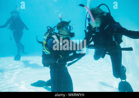 Friends on scuba training submerged in swimming pool on their holidays Stock Photo